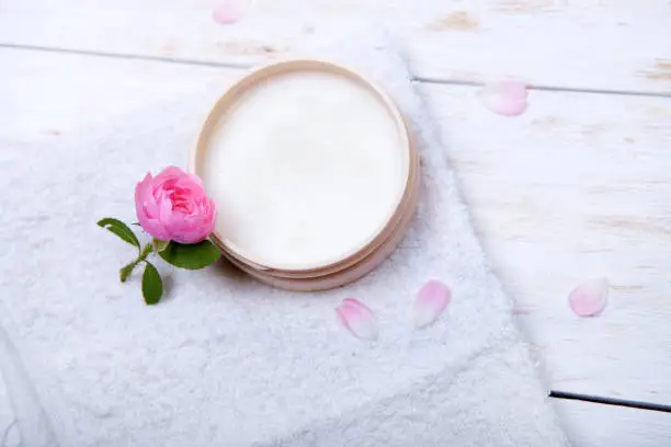 face-cream and flower on a white wooden background. natural organic cosmetic facial.