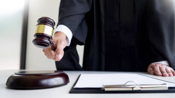 istock Midsection Of Judge Holding Gavel At Table In Courthouse 903989616