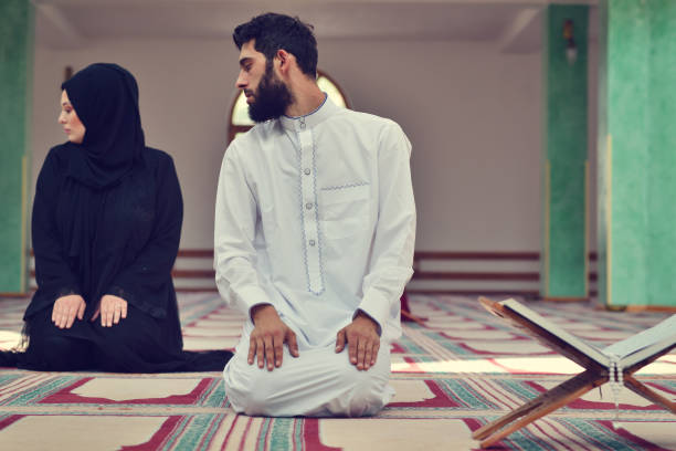 Muslim man and woman praying in mosque Muslim man and woman praying in mosque. hari raya family stock pictures, royalty-free photos & images