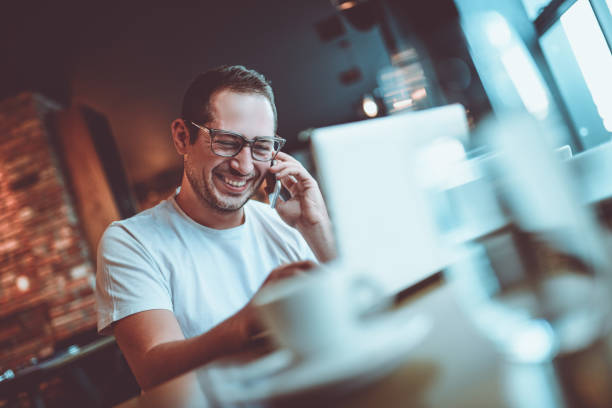 istock Young Smiling Man Talking on Mobile Phone in Coffee Restaurant 904007504