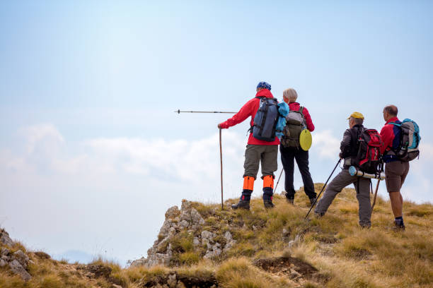 Two hikers ascend a rocky mountainside, surrounded by rugged terrain and clear skies. Equipped with backpacks, they exemplify teamwork, perseverance, and love for adventure in the great outdoors, relishing nature.