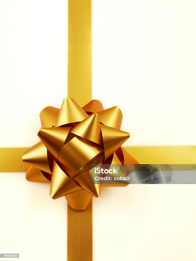 Golden bow and ribbon on cream wrapping paper Golden Ribbon and Bow on a white background with soft shadows Box - Container Stock Photo