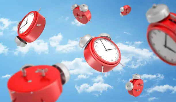 Photo of 3d rendering of a many red round retro alarm clocks falling down on the background of a blue sky with white clouds