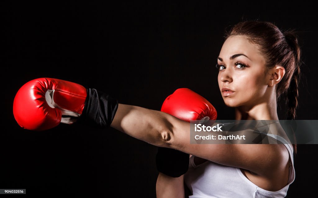 Beautiful young woman in a red boxing gloves Beautiful young woman in a red boxing gloves over black background Boxing Glove Stock Photo