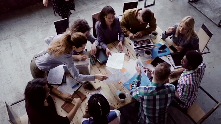 Business meeting at modern office. Top view of multiracial group of people working near the table together. Slow mo