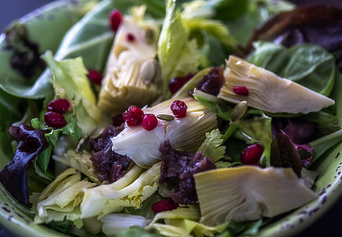A colourful salad ,  pomegranate seeds, artichokes and onion jam on a bed of green leaves