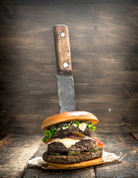 istock Fast food. A fresh burger made from beef and vegetables with a large knife. 904033310