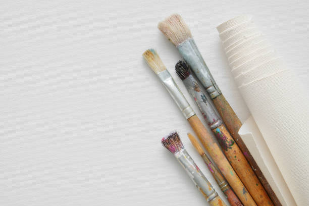 istock Paintbrushes and roll of artist canvas on white canvas background. Top view. Copy space for text. 904044006