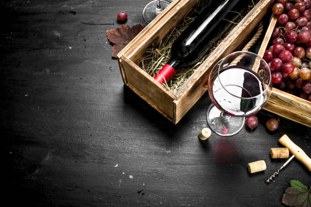 istock Wine background. Red wine in an old box with a corkscrew. 904044526