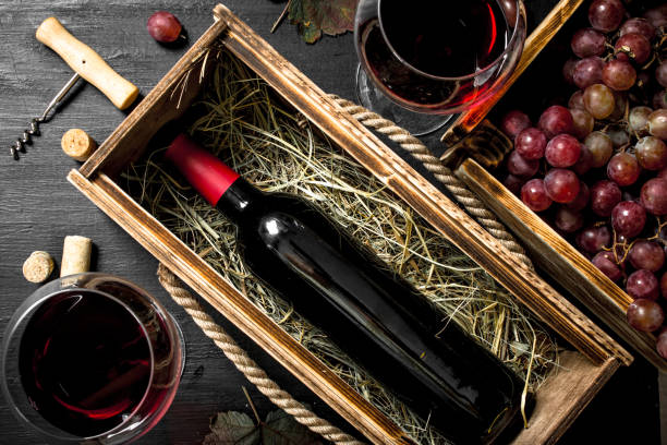 istock Wine background. Red wine in an old box with a corkscrew. 904044538