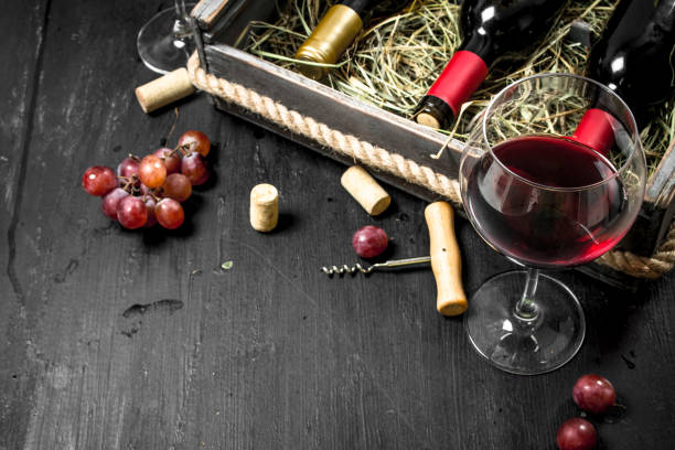 istock Wine background. Red wine in an old box with a corkscrew. 904044710