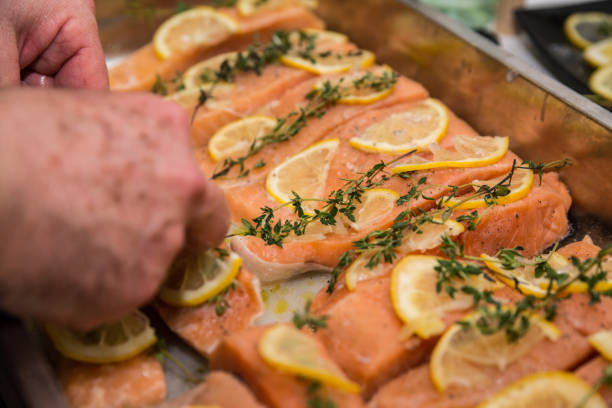 istock Roasted salmon and vegetables. Hand putting lemon on fish 904045480