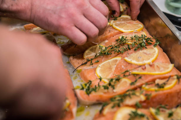 istock Roasted salmon and vegetables. Hand putting lemon on fish 904045606