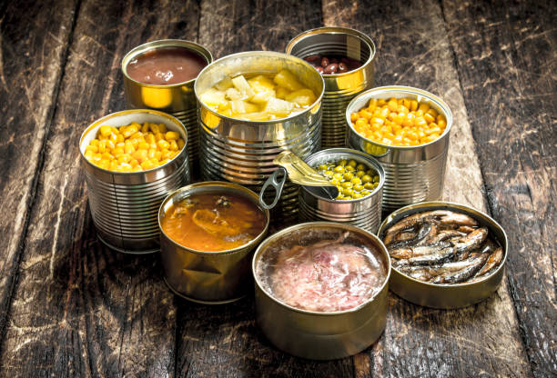 Various canned vegetables, meat, fish and fruits in tin cans. Various canned vegetables, meat, fish and fruits in tin cans. On a wooden background. canned food stock pictures, royalty-free photos & images