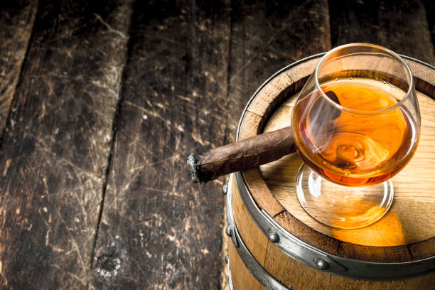 istock glass of cognac with a cigar on a barrel. 904063716