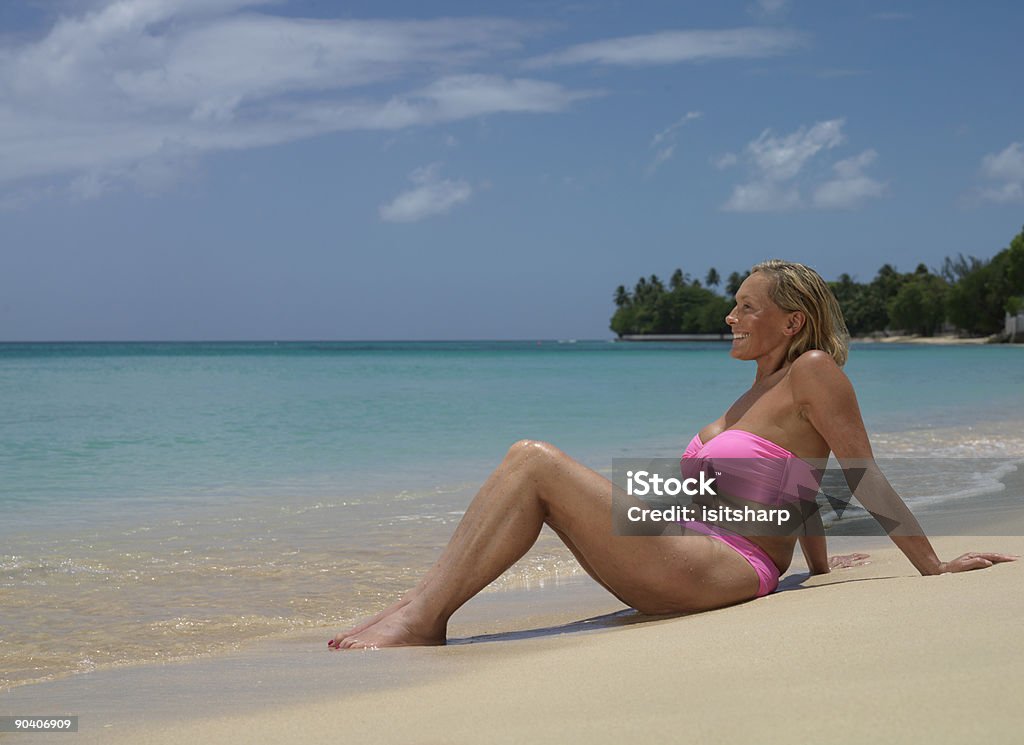 Donna seduta sulla spiaggia - Foto stock royalty-free di Adagiarsi