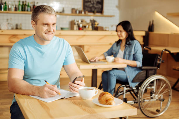 istock Happy man taking notes and a disabled woman behind him 904073562
