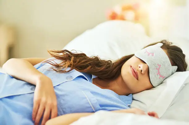 Cropped shot of an attractive young woman wearing a sleep mask while lying in bed