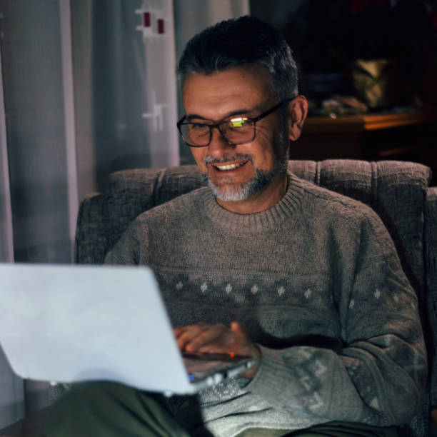 istock Smiling man sitting on sofa with laptop 904082638