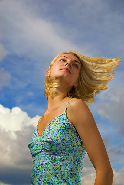 美しい金髪の少女青い空と雲の後ろに彼女の - blond hair overcast sun sky ストックフォトと画像