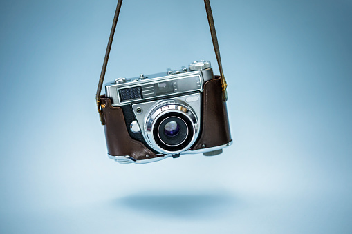 Hanging  realistic photo camera over blue background