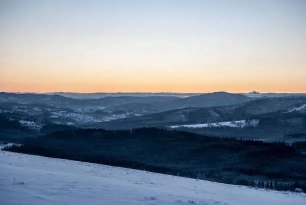 daylight from Ochodzita hill in winter Beskid Slaski mountains above Koniakow village in Poland with clear colorful sky, snow and hills