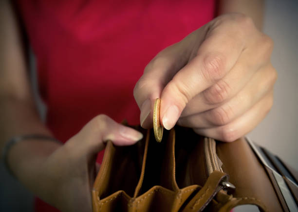 young woman putting a coin in a wallet. - women savings uk coin imagens e fotografias de stock