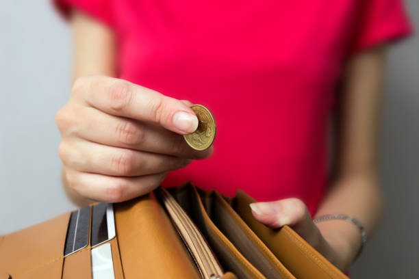 una giovane donna che mette una moneta in un portafoglio. - pound symbol red british currency symbol foto e immagini stock