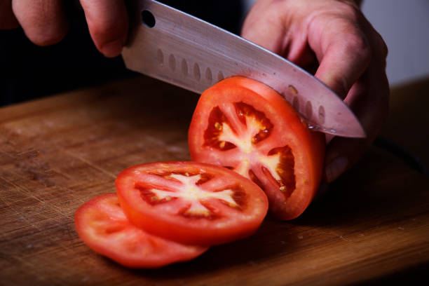 鋭いナイフでスライスされるトマト - vegetable cutter ストックフォトと画像