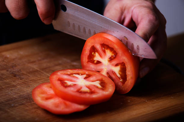 Tomato being sliced with a sharp knife Tomato being sliced with a sharp kitchen knife chopping food stock pictures, royalty-free photos & images