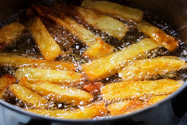 freír patatas fritas en aceite caliente burbujeante - frito fotos fotografías e imágenes de stock