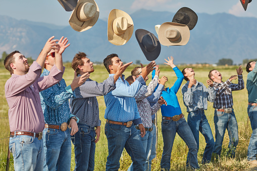 Cowboys and Cowgirls celebrating throwing their hats in the air.