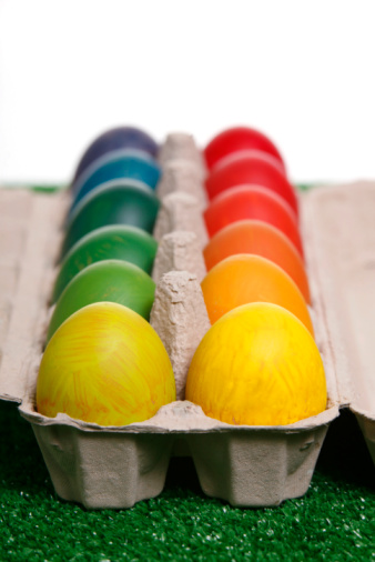Multicolored Easter eggs, Paschal eggs, in a egg carton. Hard boiled, colorful dyed chicken eggs, used to celebrate the resurrection of Jesus during Eastertide. Symbol for fertility and rebirth.