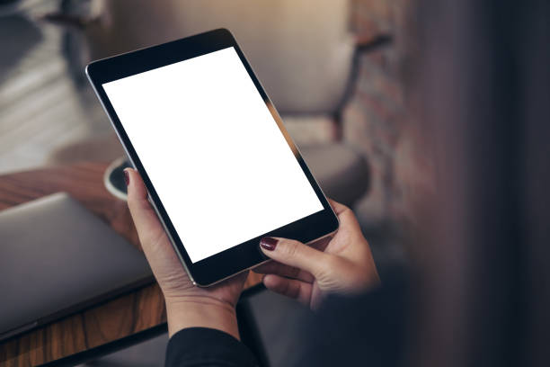 istock Mockup image of woman's hands holding and looking at black tablet pc with blank white desktop screen in cafe 904105428
