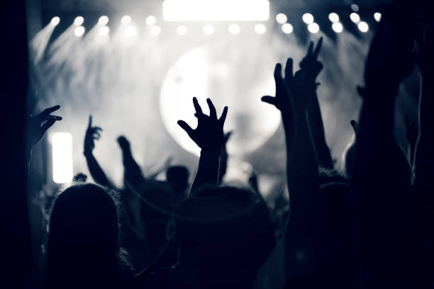 istock Crowd at a music concert, audience raising hands up, toned 904106172