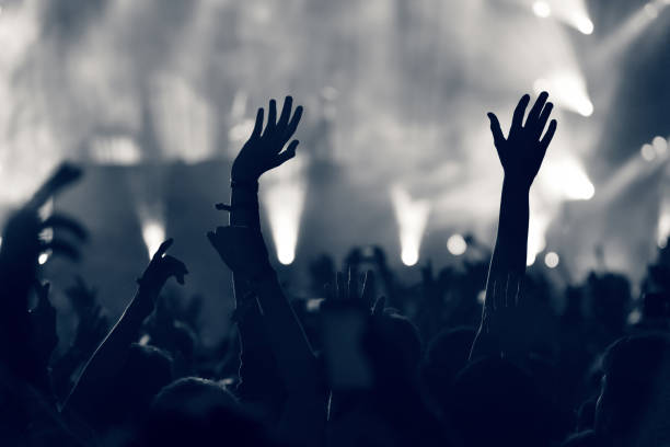istock Crowd at a music concert, audience raising hands up, toned 904106520