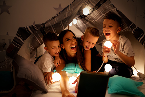 Children  in homemade tent at home having fun with mother