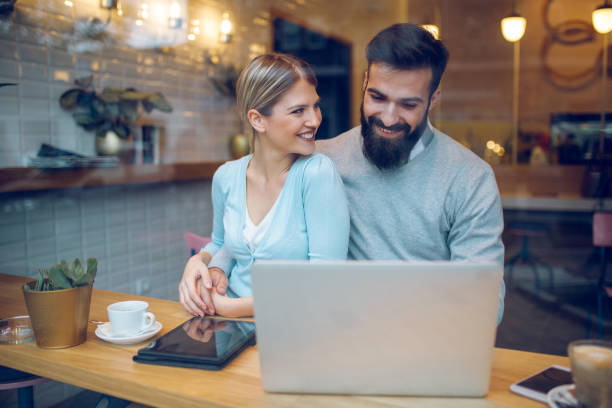 istock Happy couple sitting in cafe with laptop and web surfing 904121998