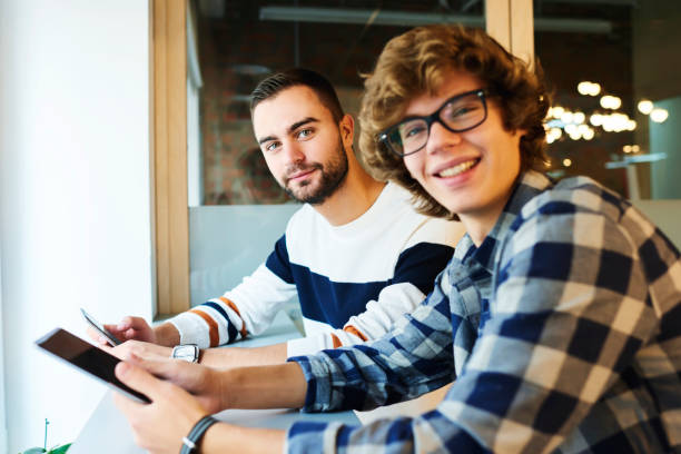 istock Smiling handsome young international students resting after lesson in university sitting in campus enjoying leisure playing online games on modern gadgets using free wireless connection to internet 904127498