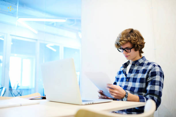 istock Smiling skilled male web designer making sketch for his new brilliant idea for interior project thinking over details drawing in notebook while sitting in coworking space with laptop computer and wifi 904127584