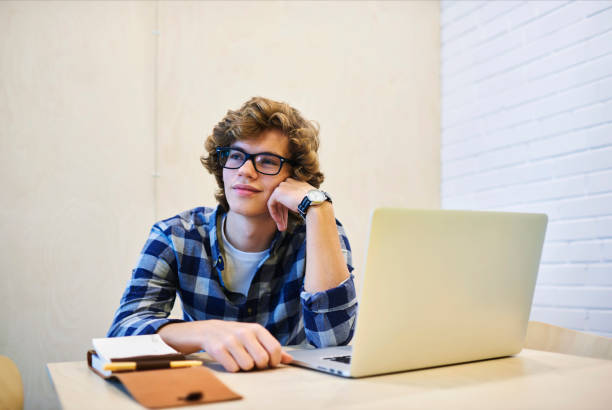istock Pensive young handsome male international student of journalism thinking over creative idea for article concentrated doing homework after lessons sitting in college library with laptop computer 904127590