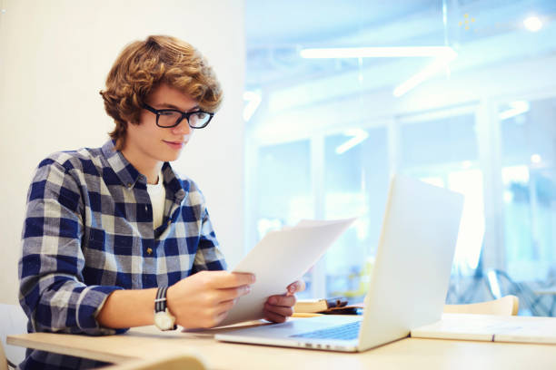 istock Professional young male project manager of IT corporation reading reports about working process in office sitting near copy space area for advertising; student improving knowledge reading report 904127672