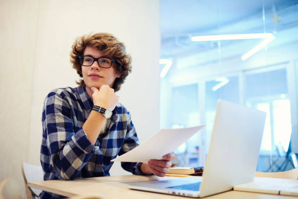 istock Pensive talented male journalist proofreading article for publication on web site thinking about improvement text and content of online issue while working on promotional background in office 904127704