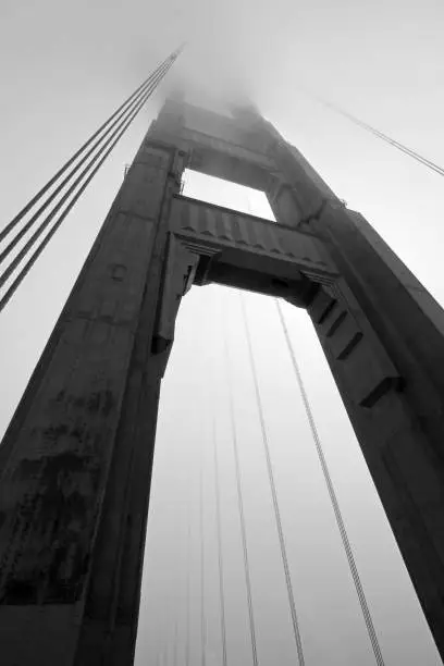 Photo of Golden Gate Bridge tower in black and white with fog rolling, San Francisco