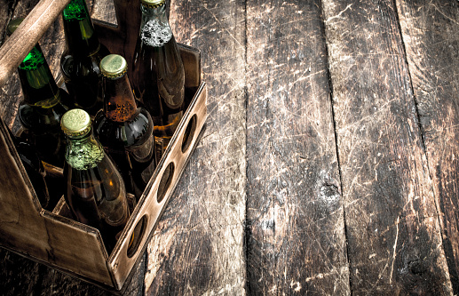 box with bottles of fresh beer. On a wooden background.