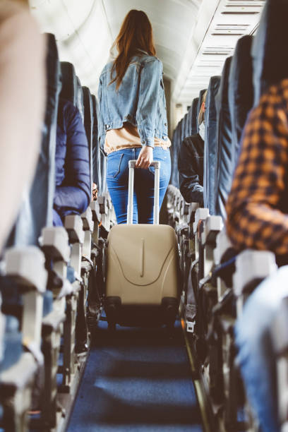 istock Airplane interior with woman carrying suitcase 904136632