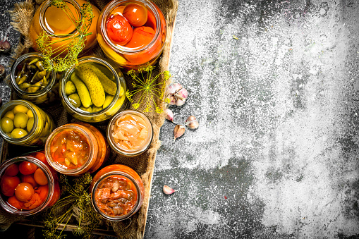 Preserved vegetables with mushrooms on an old tray. On a rustic background.