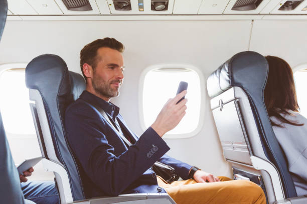 hombre viaja en avión y usar teléfono móvil - telephone cabin fotografías e imágenes de stock