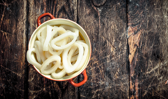 Rings of sea squid in a bowl. On a wooden background.