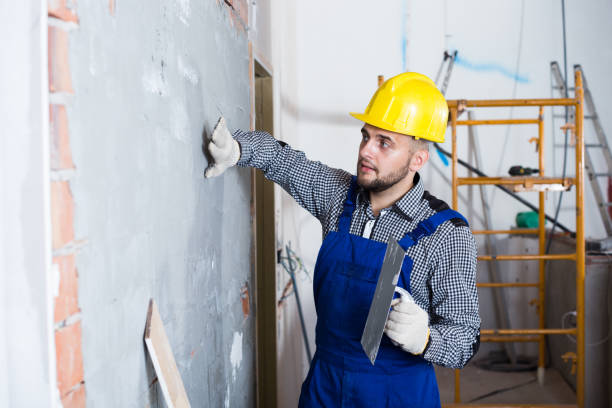 istock Male builder is checking the quality of the work done after the plaster wall 904142604